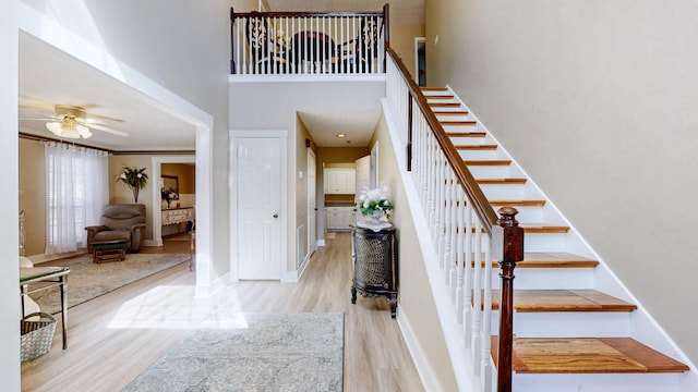 foyer entrance featuring a ceiling fan, stairs, baseboards, and wood finished floors