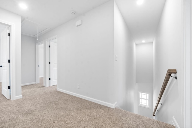 hall with carpet, attic access, baseboards, and an upstairs landing