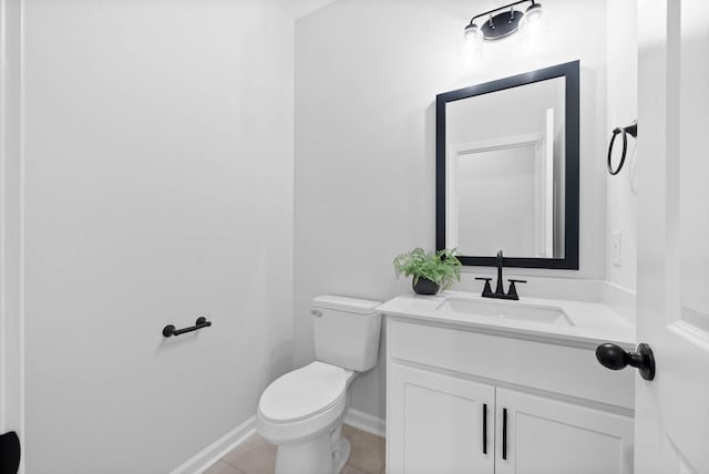 half bath with toilet, tile patterned flooring, baseboards, and vanity