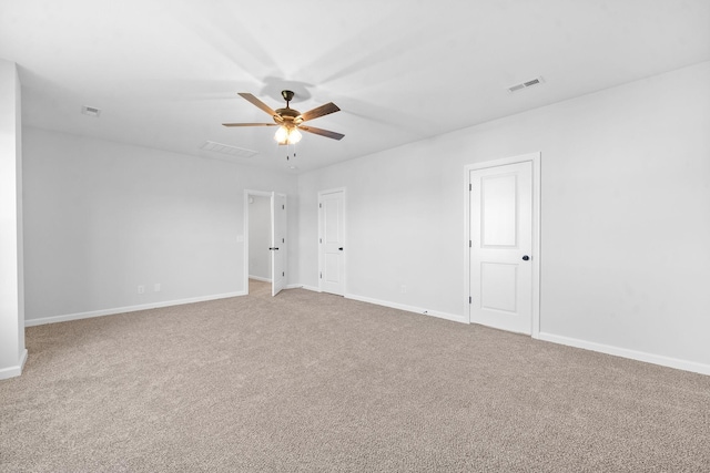 empty room featuring carpet floors, visible vents, baseboards, and a ceiling fan