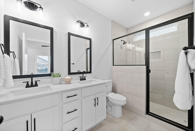 bathroom with double vanity, a stall shower, a sink, and toilet