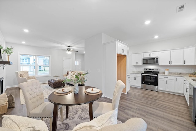 dining room with recessed lighting, visible vents, a fireplace, and light wood finished floors