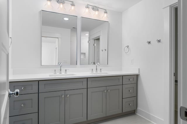 bathroom with double vanity, tile patterned flooring, baseboards, and a sink