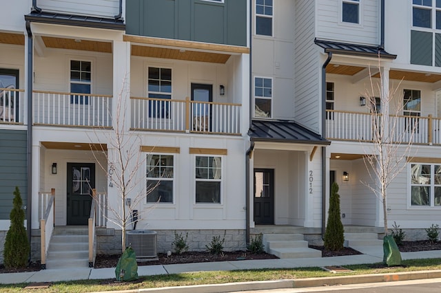 view of front facade featuring a standing seam roof, central AC unit, metal roof, and board and batten siding