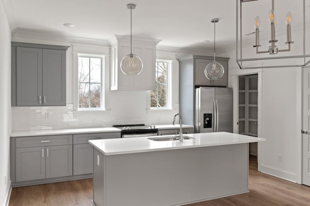 kitchen featuring crown molding, stainless steel appliances, gray cabinets, light wood-style floors, and a sink