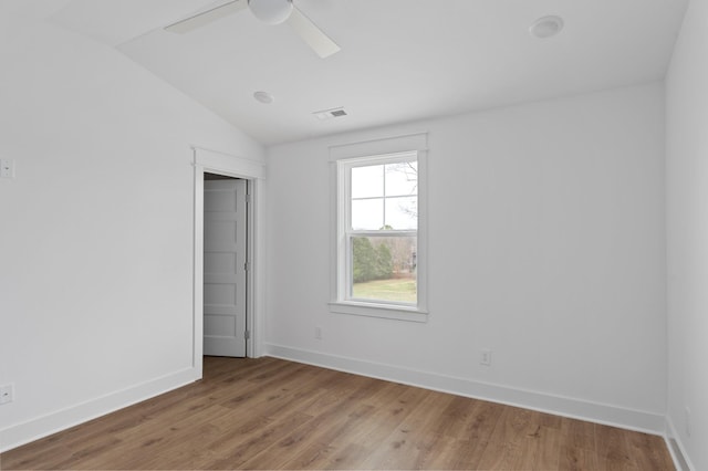 empty room with light wood-style floors, baseboards, visible vents, and vaulted ceiling