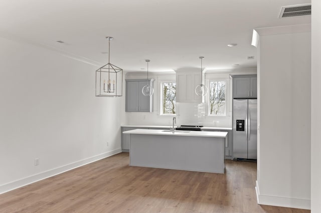 kitchen featuring gray cabinetry, a center island with sink, visible vents, and stainless steel fridge with ice dispenser