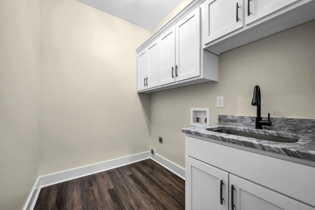 washroom featuring cabinet space, baseboards, dark wood-style floors, washer hookup, and a sink