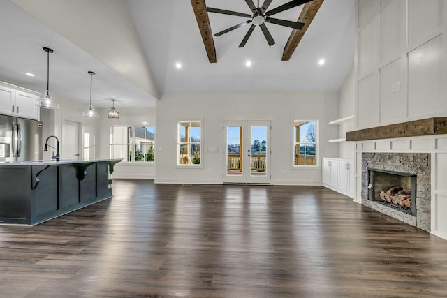 unfurnished living room with a ceiling fan, dark wood-style flooring, a fireplace, and beam ceiling