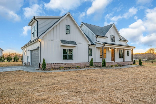 modern farmhouse style home featuring an attached garage, covered porch, brick siding, driveway, and board and batten siding