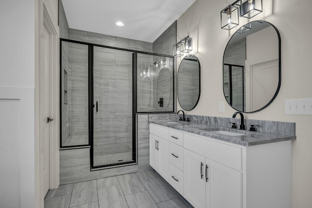 bathroom with a stall shower, a sink, and double vanity