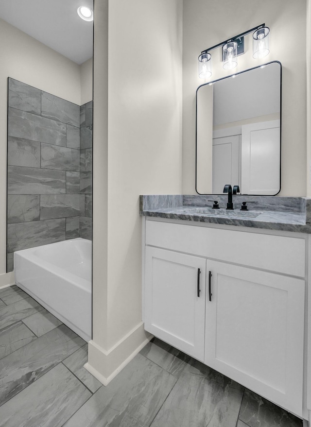 bathroom with marble finish floor, vanity, and baseboards