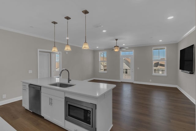 kitchen with a sink, stainless steel microwave, dark wood finished floors, light countertops, and dishwashing machine