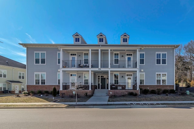 view of front of home with brick siding, a porch, and a balcony