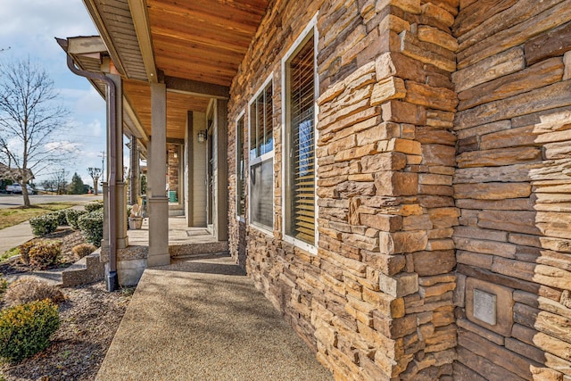 view of side of property with stone siding and covered porch