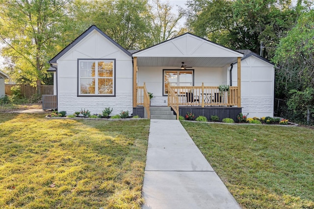 view of front of property featuring a porch, a front yard, stone siding, and ceiling fan