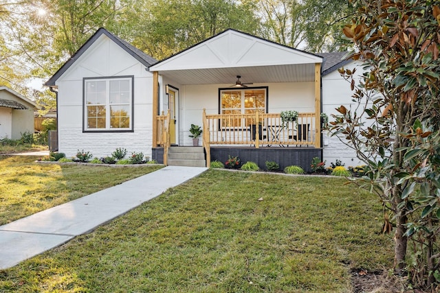 view of front facade featuring covered porch, stone siding, cooling unit, and a front yard