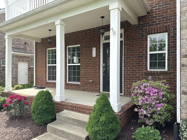 doorway to property featuring a porch and brick siding