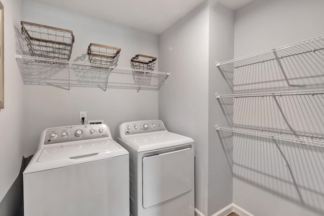 clothes washing area featuring laundry area, baseboards, and separate washer and dryer