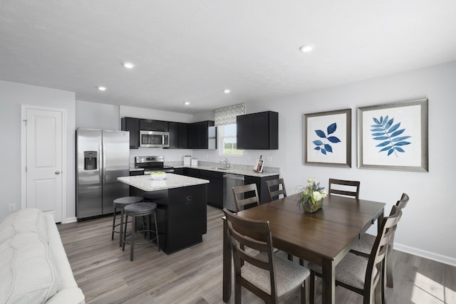 dining space featuring baseboards, light wood-type flooring, and recessed lighting