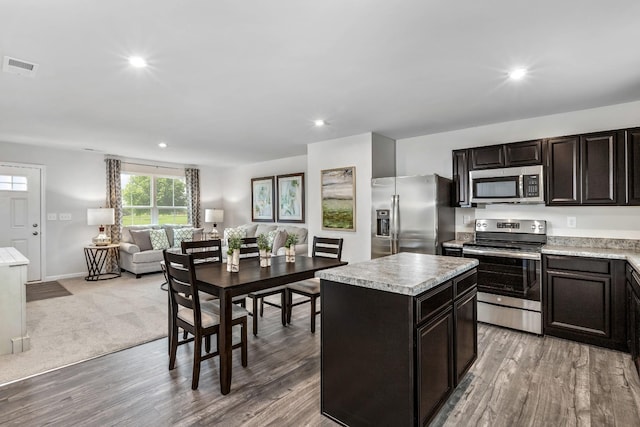 kitchen featuring stainless steel appliances, visible vents, open floor plan, light countertops, and a center island