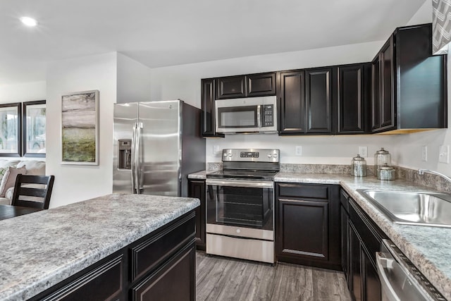 kitchen featuring stainless steel appliances, recessed lighting, light countertops, light wood-style flooring, and a sink