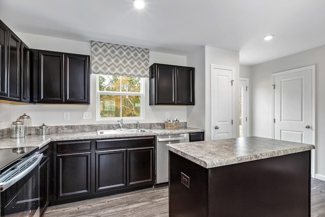 kitchen featuring a kitchen island, appliances with stainless steel finishes, light wood-type flooring, a sink, and recessed lighting