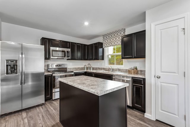 kitchen featuring appliances with stainless steel finishes, a kitchen island, a sink, and wood finished floors