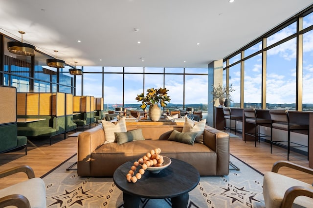 living room with a wall of windows, wood finished floors, and recessed lighting