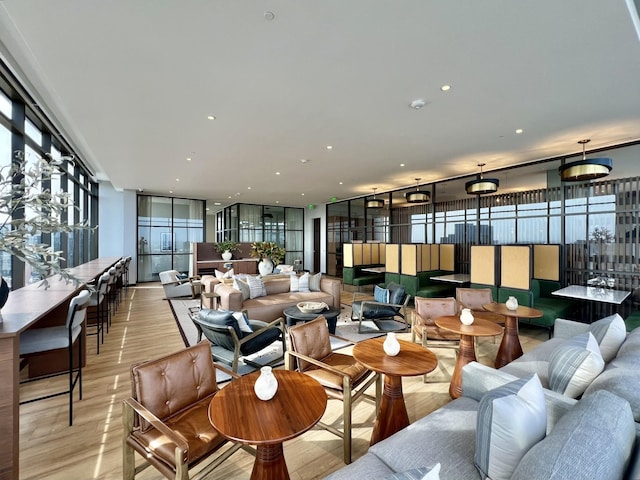 living room with light wood finished floors, recessed lighting, and a wall of windows