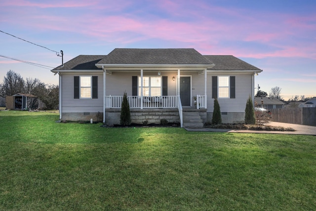 view of front facade with roof with shingles, covered porch, a front yard, crawl space, and fence