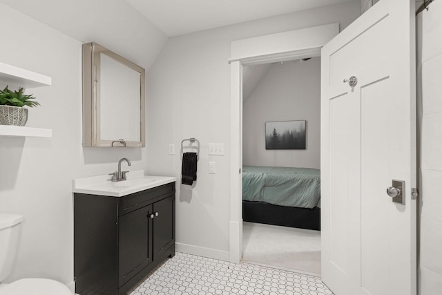 ensuite bathroom featuring baseboards, ensuite bath, vanity, and toilet