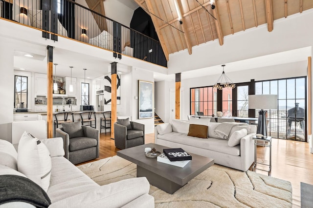 living area with wooden ceiling, wood finished floors, an inviting chandelier, stairs, and high vaulted ceiling