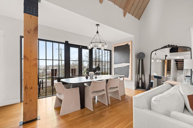 dining room featuring a chandelier, high vaulted ceiling, and light wood-style flooring