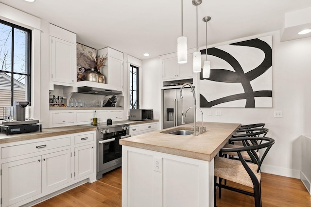 kitchen featuring light wood-type flooring, white cabinetry, stainless steel appliances, and a kitchen breakfast bar