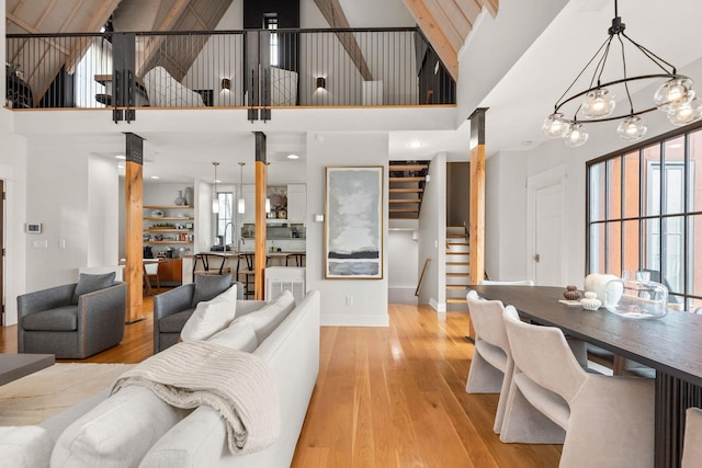 living area with a chandelier, light wood-type flooring, plenty of natural light, and stairway