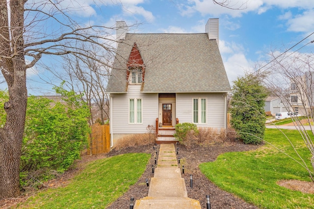 view of front facade featuring a shingled roof, fence, a chimney, and a front lawn