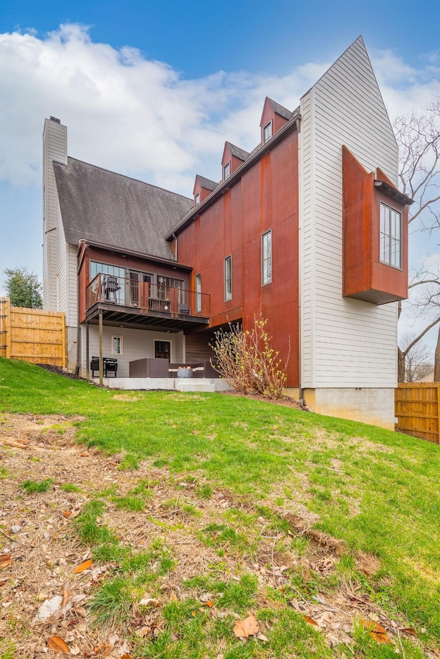 rear view of house featuring a patio area, fence, a wooden deck, and a lawn