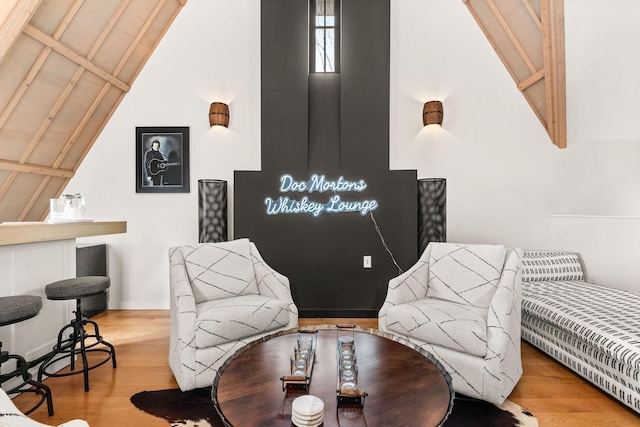 living area featuring vaulted ceiling, wood finished floors, and baseboards