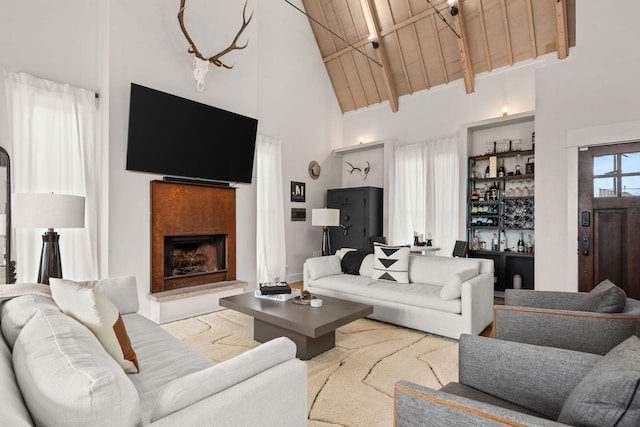 living room with a dry bar, a fireplace with raised hearth, wood ceiling, beamed ceiling, and high vaulted ceiling