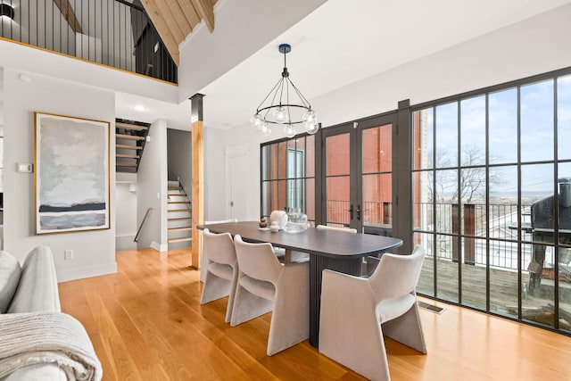 dining space featuring a chandelier, light wood-style flooring, visible vents, baseboards, and stairs