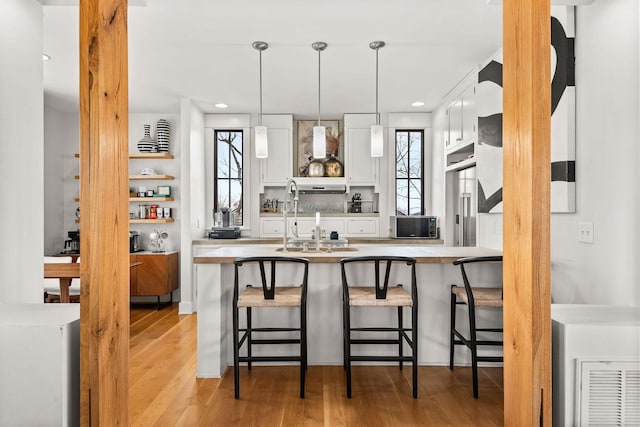 kitchen featuring light countertops, a breakfast bar area, white cabinets, and light wood-style floors