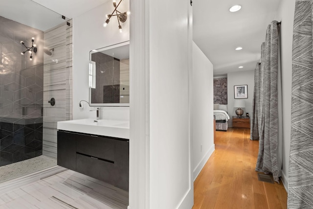 full bath featuring recessed lighting, vanity, wood finished floors, baseboards, and a walk in shower