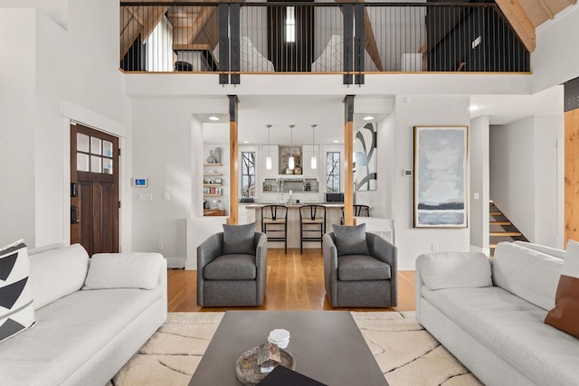 living room with stairs, a high ceiling, wood finished floors, and baseboards