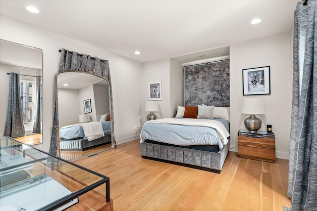 bedroom featuring light wood-type flooring, baseboards, arched walkways, and recessed lighting