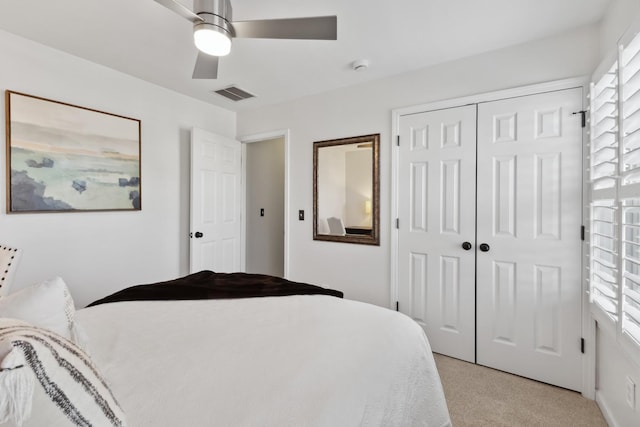 bedroom with light carpet, a ceiling fan, visible vents, and a closet