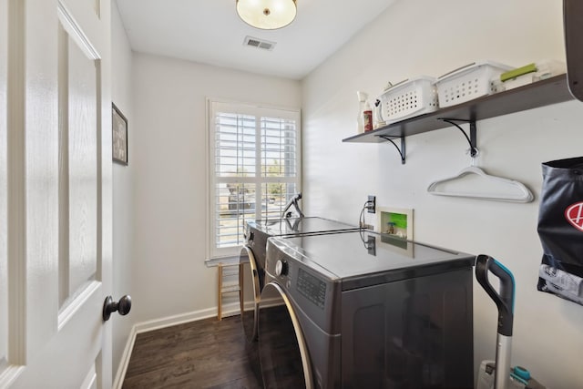 laundry area with laundry area, visible vents, baseboards, dark wood-style floors, and washing machine and clothes dryer