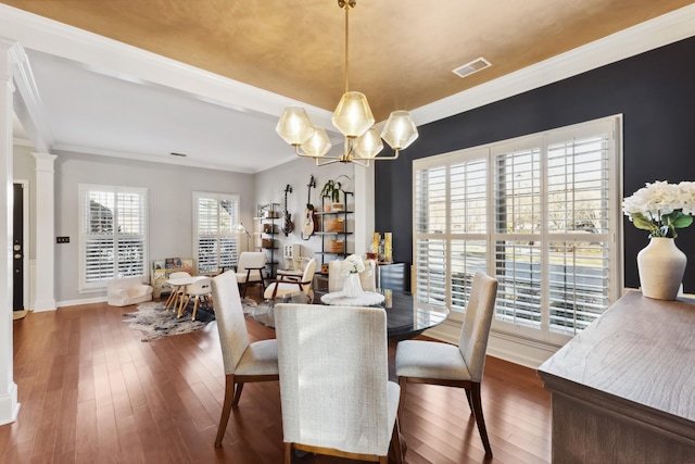 dining room with ornamental molding, hardwood / wood-style flooring, visible vents, and an inviting chandelier