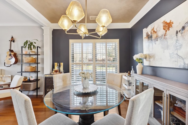 dining room with wood finished floors, visible vents, ornamental molding, ornate columns, and an inviting chandelier