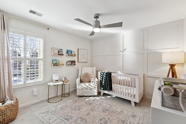 carpeted bedroom featuring a crib, visible vents, and baseboards